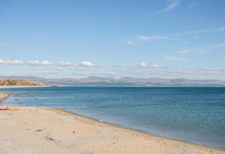 Vista da 'Susanna' Poachers Hut su una spiaggia tranquilla, mare blu e colline lontane nel Regno Unito.