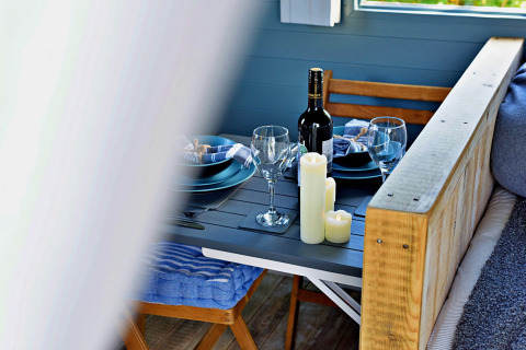 Tavola accogliente con vino, candele e piatti blu nel mobil home 'Susanna' Poachers Hut, Regno Unito.