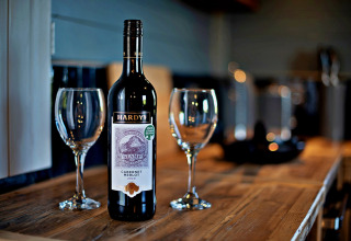 Una bottiglia di Hardys Cabernet Merlot 2020 e due calici su tavolo in legno nel mobilhome 'Susanna' Poachers Hut, Regno Unito.