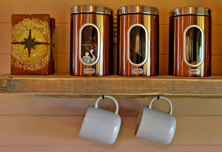 Shelf with three copper canisters and two hanging mugs in the cozy 'Marared' Gypsy Hut, United Kingdom.