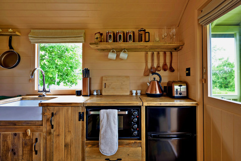 Stemningsfuld lille køkken i træ fra 'Marared' Gypsy Hut i Storbritannien, med rustikke detaljer og udsigt.