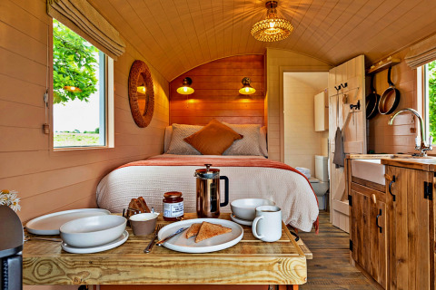Interior of 'Marared' Gypsy Hut, featuring a cozy tiny house with bed, kitchenette, and breakfast on table.