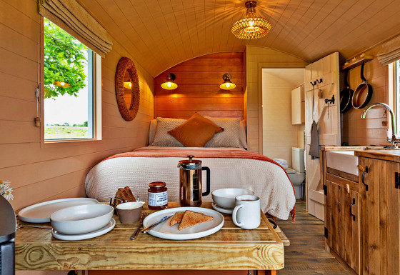 Interior of 'Marared' Gypsy Hut, featuring a cozy tiny house with bed, kitchenette, and breakfast on table.