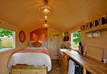 Gemütliches Tiny House 'Marared' Gypsy Hut im Vereinigten Königreich mit Bett, Holzdekor und Küche.