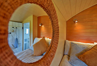 Cozy view of the bedroom in the 'Marared' Gypsy Hut, reflected in a round mirror, United Kingdom.