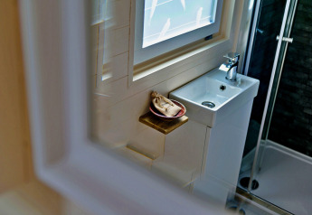 Badezimmer im 'Marared' Gypsy Hut mit kleinem Waschbecken, Fenster und Dusche in Großbritannien.