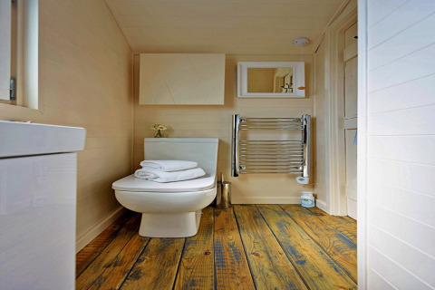 Modern bathroom in the tiny house 'Marared' Gypsy Hut in the UK with wood floors and white furnishings.