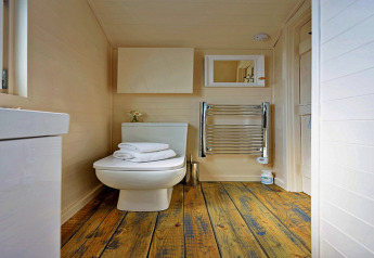 Modernes Badezimmer im kleinen Haus 'Marared' Gypsy Hut, Großbritannien, mit Holzboden und weißen Details.