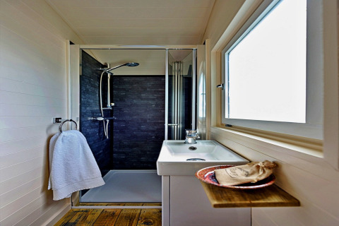 Modern compact bathroom in 'Marared' Gypsy Hut, featuring shower and wood accents, United Kingdom.