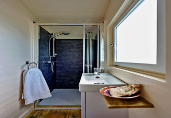 Modernes, kompaktes Badezimmer in der 'Marared' Gypsy Hut mit Dusche und Holzakzenten im Vereinigten Königreich.