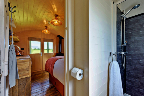 Blick in das 'Marared' Gypsy Hut Tiny House in Großbritannien mit gemütlichem Schlafzimmer und Badezimmer.