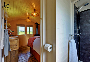 Blick in das 'Marared' Gypsy Hut Tiny House in Großbritannien mit gemütlichem Schlafzimmer und Badezimmer.