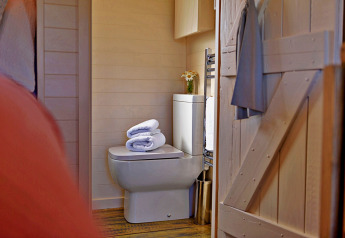 Kleines Badezimmer in der 'Marared' Gypsy Hut in Großbritannien mit WC, Handtüchern und Blumen.