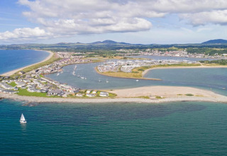 Aerial view from 'Marared' Gypsy Hut, UK, showing the coastline, a marina with boats, and a small sailboat.
