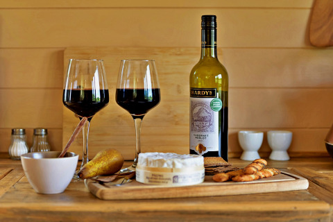 Red wine, two glasses, cheese, crackers and pear on wooden table in 'Marared' Gypsy Hut, Tiny House, UK.