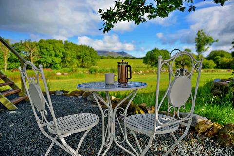 Outdoor table and two chairs with coffee pot and mug, scenic greenery at 'Marared' Gypsy Hut, United Kingdom