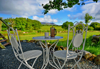 Gartentisch mit zwei Stühlen, einer Kaffeekanne und Tasse im Grünen bei 'Marared' Gypsy Hut, Großbritannien