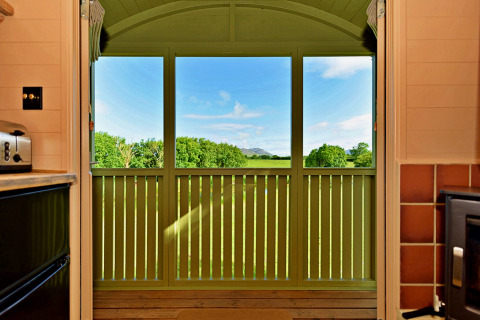 View from the kitchen in 'Marared' Gypsy Hut, showing green fields and hills in the UK countryside.