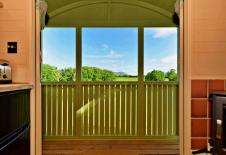 View from the kitchen in 'Marared' Gypsy Hut, showing green fields and hills in the UK countryside.