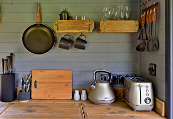 Compacte keuken in mobiele woonwagen met pan, broodrooster, waterkoker en houten rekjes