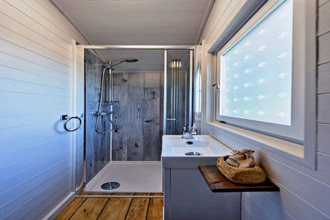 Salle de bain moderne dans la roulotte 'Elen' Gypsy Hut avec douche, lavabo et fenêtre givrée au Royaume-Uni.