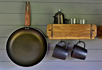 Keukenhoek in 'Elen' Gypsy Hut met pan, kopjes, metalen kan en glazen op houten rek in het Verenigd Koninkrijk.