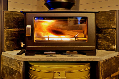 Poêle à bois avec feu visible à l'intérieur, dans la tiny house mobile 'Elen' Gypsy Hut au Royaume-Uni.