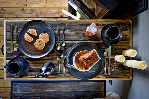 Table rustique avec gâteau, café et bougies dans la 'Elen' Gypsy Hut, Royaume-Uni, vue du dessus.