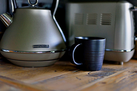 Une tasse noire sur une table en bois, près d'une bouilloire et d'un grille-pain Morphy Richards, dans une roulotte.