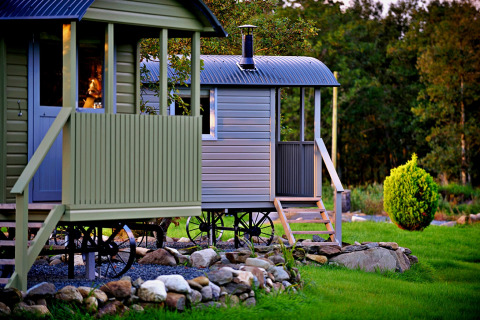 Photo de la 'Elen' Gypsy Hut, maison mobile sur roues avec terrasse et jardin de pierres, en nature.