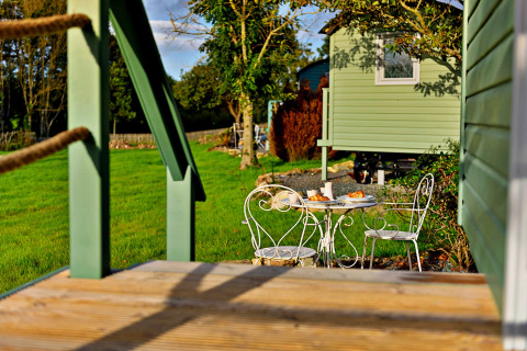 Havebord med morgenmad foran en grøn mobilhome i naturskønne omgivelser i Storbritannien.