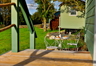 Havebord med morgenmad foran en grøn mobilhome i naturskønne omgivelser i Storbritannien.