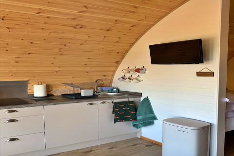 Petite cuisine moderne avec évier, tasses, serviettes et télévision dans le pod « Worm Dale » au Royaume-Uni.