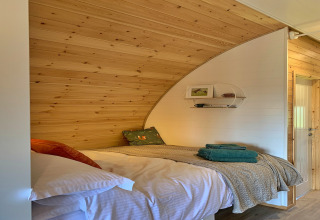 Coin nuit douillet dans la pod Worm Dale au Royaume-Uni, avec bois, lit confortable et serviettes pliées.