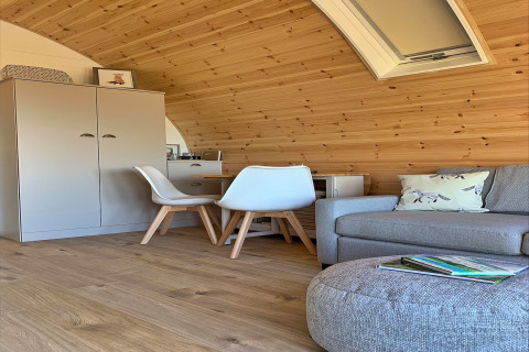 Vue intérieure d’une pod chaleureuse nommée « Worm Dale » au Royaume-Uni, avec des murs en bois et un canapé.