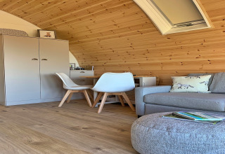 Vue intérieure d’une pod chaleureuse nommée « Worm Dale » au Royaume-Uni, avec des murs en bois et un canapé.