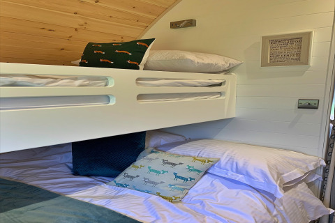 Chambre de pod moderne avec lits superposés, coussins à motifs et plafond en bois à Worm Dale, Royaume-Uni.