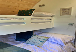 Chambre de pod moderne avec lits superposés, coussins à motifs et plafond en bois à Worm Dale, Royaume-Uni.