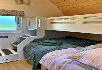 Knusse slaaphoek in de Worm Dale pod, Verenigd Koninkrijk, met moderne stapelbedden en raam.