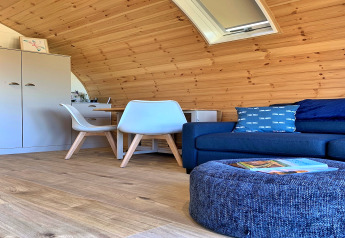 Gezellige houten pod met zetel, kussens, stoelen en tafel in Deep Dale, Verenigd Koninkrijk.