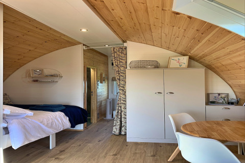 Cozy interior of the 'Deep Dale' pod in the United Kingdom, featuring wood paneling, a bed, and modern furniture.