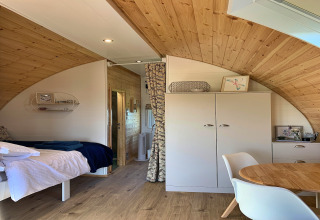 Cozy interior of the 'Deep Dale' pod in the United Kingdom, featuring wood paneling, a bed, and modern furniture.