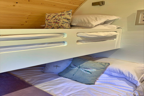 Modern bunk beds in the 'Deep Dale' pod in the UK, decorated with dragonfly-themed cushions and bedding.