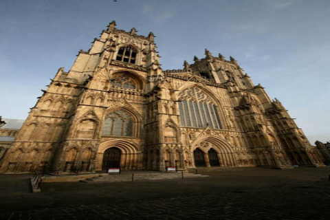 Photo of a grand Gothic cathedral with tall towers and intricate windows, taken from a low angle view.