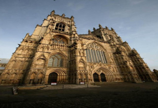 Photo of a grand Gothic cathedral with tall towers and intricate windows, taken from a low angle view.
