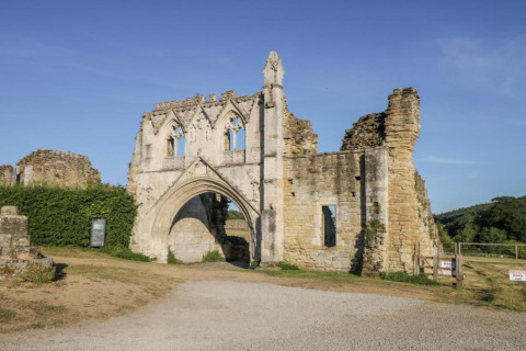Ruines du pod Worm Dale au Royaume-Uni, montrant des murs de pierre et une arche sous un ciel bleu.