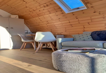 Hyggelig interiør med træpaneler, loftvindue, sofa, stole og bord i en pod ved Mingle Dale, Storbritannien.