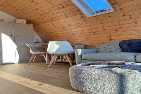 Hyggelig interiør med træpaneler, loftvindue, sofa, stole og bord i en pod ved Mingle Dale, Storbritannien.