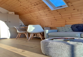 Hyggelig interiør med træpaneler, loftvindue, sofa, stole og bord i en pod ved Mingle Dale, Storbritannien.