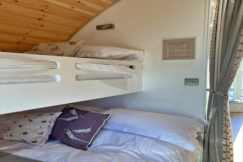 Moderne køjesenge i en hyggelig pod med træloft, bløde puder og naturligt lys ved Mingle Dale, UK.